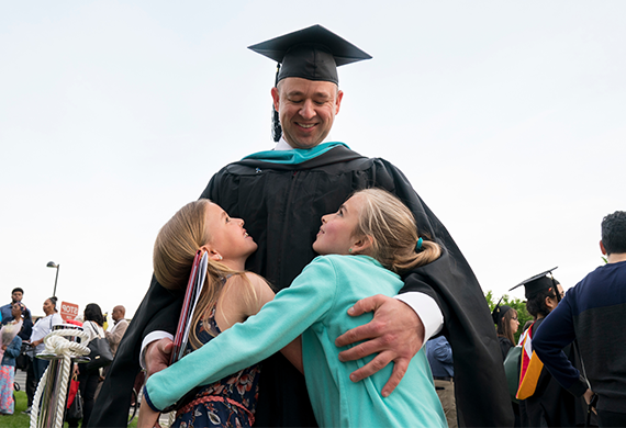 一张成年毕业生拥抱两个孩子的照片.